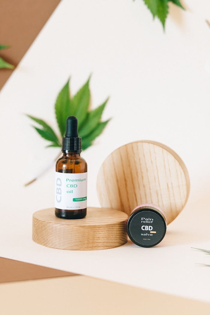 Minimalist display of CBD oil and salve with cannabis leaf backdrop, perfect for wellness themes.