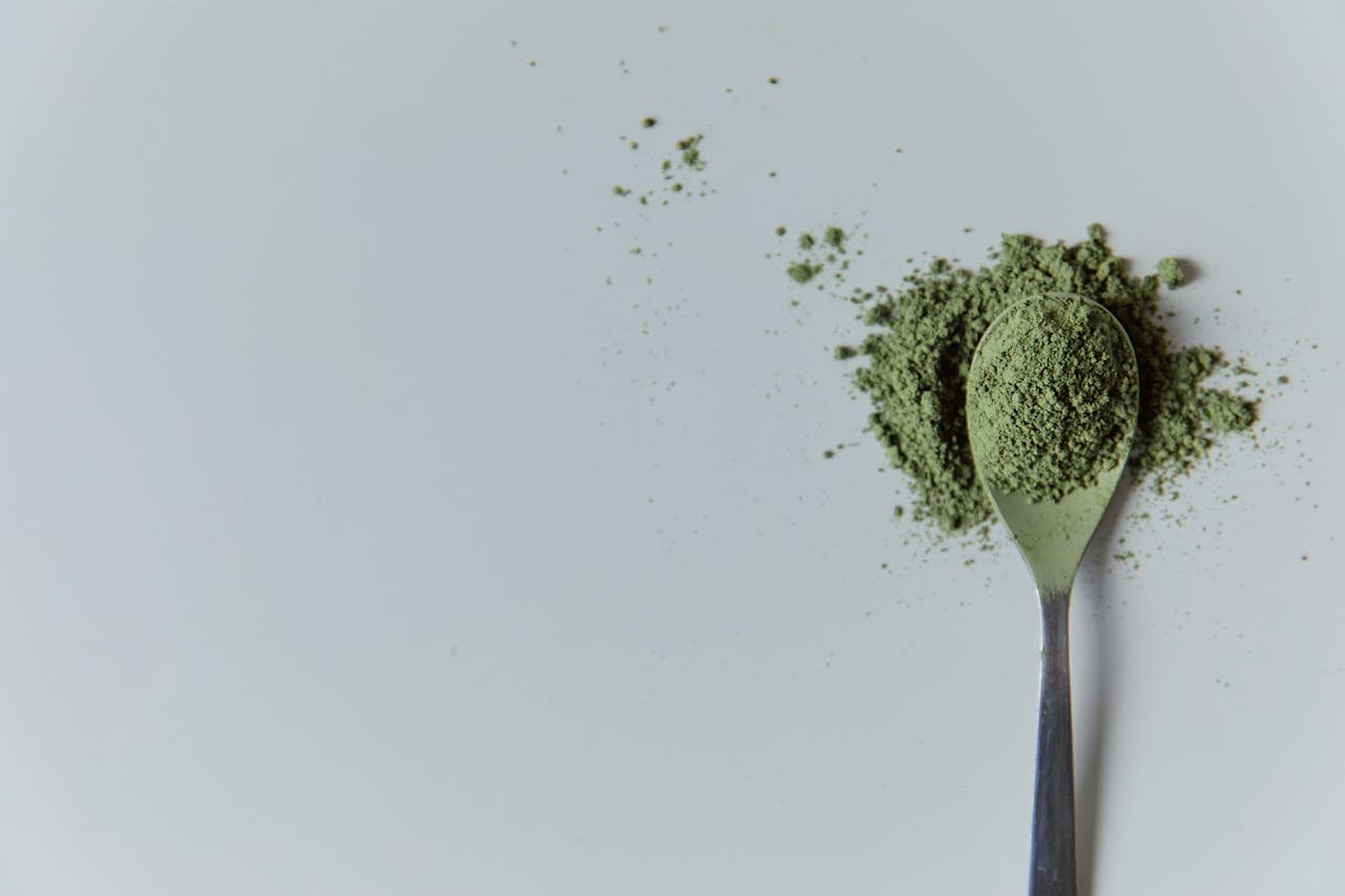 High-quality matcha powder on a spoon in a minimalist studio setting, ideal for culinary and wellness themes.